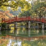 AI-generated illustration of a red arched bridge reflected in a tree-lined pond, inspired by Dazaifu Tenmangu.