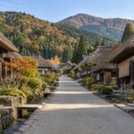 AI-generated illustration of thatched-roof houses beside a quiet village lane, inspired by Ouchi-juku, Fukushima, in autumn.