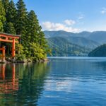 AI-generated illustration inspired by Lake Ashi in Hakone, with a red torii gate, blue water, and forested hills