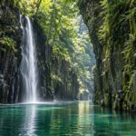 AI-generated illustration of a slender waterfall and emerald river between wooded columnar cliffs, inspired by Takachiho Gorge in Miyazaki.