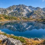 AI-generated illustration of a blue alpine lake and rugged mountains, inspired by Mikurigaike in Tateyama, Toyama, Japan.