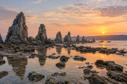 AI-generated illustration of jagged coastal rock pillars and reflective tidal pools at sunrise, inspired by Hashigui-iwa in Wakayama.